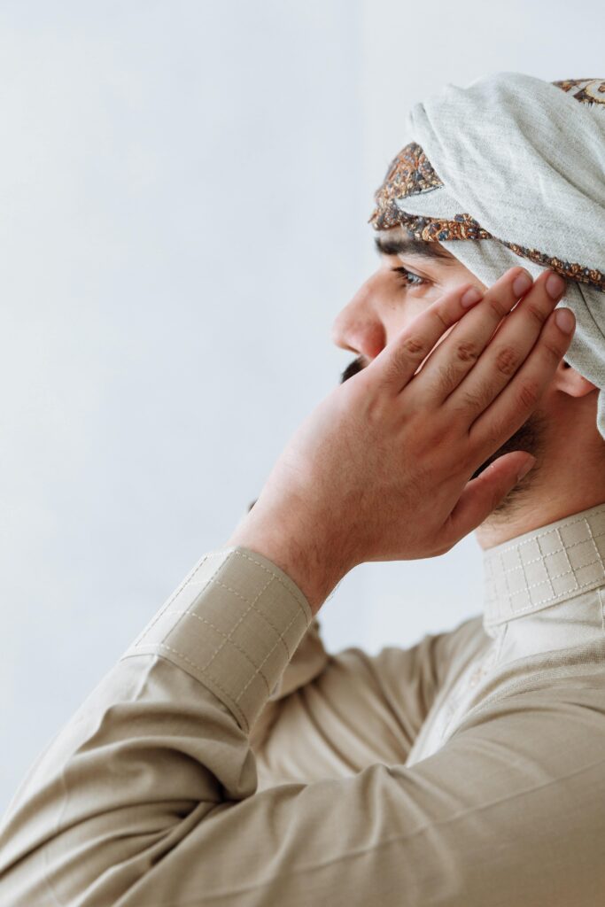 A contemplative man in traditional Middle Eastern attire praying, emphasizing spirituality and culture.